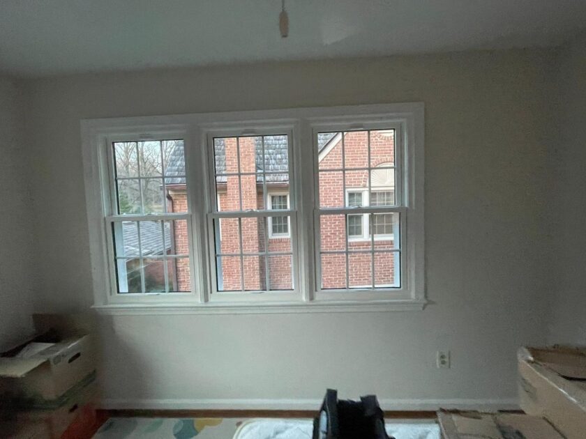 Interior view of a room with a new triple-pane window overlooking a brick residential building