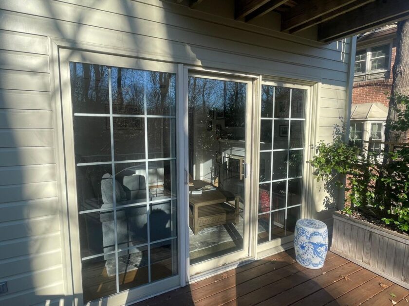 Exterior view of a house with new composite frame windows and a sliding glass door on a sunny day