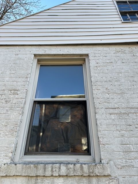 Triple pane window in a painted brick wall of a house, indicating a recent upgrade for energy efficiency