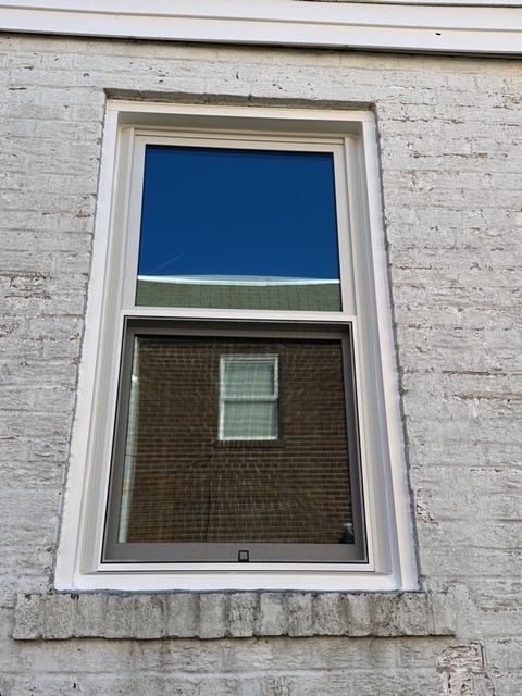 Energy-efficient triple-pane window with white frame on a white-painted brick wall
