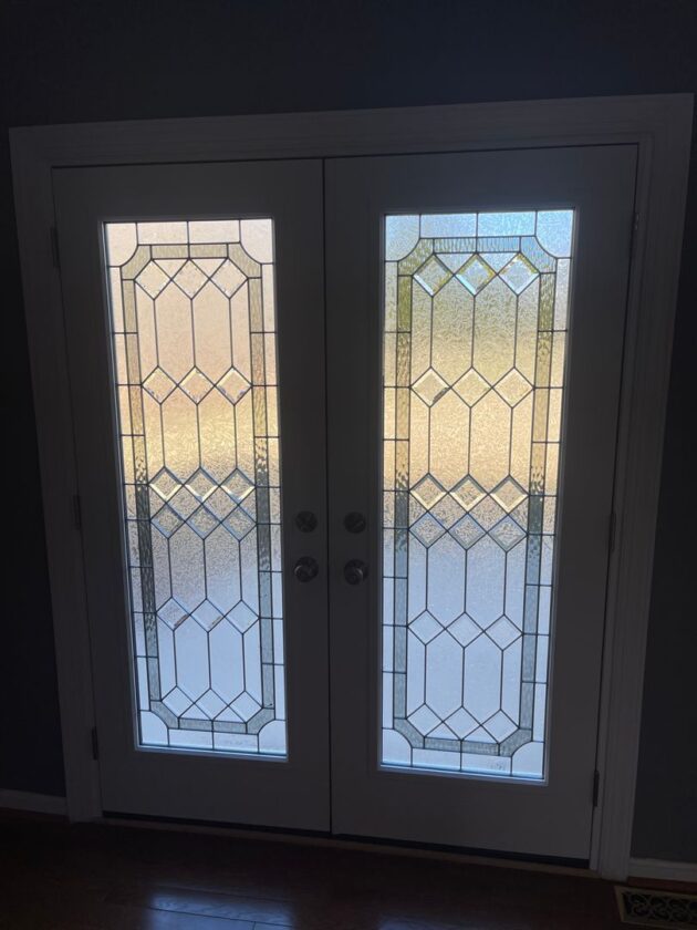 Interior view of closed French doors with geometric patterned glass sidelights